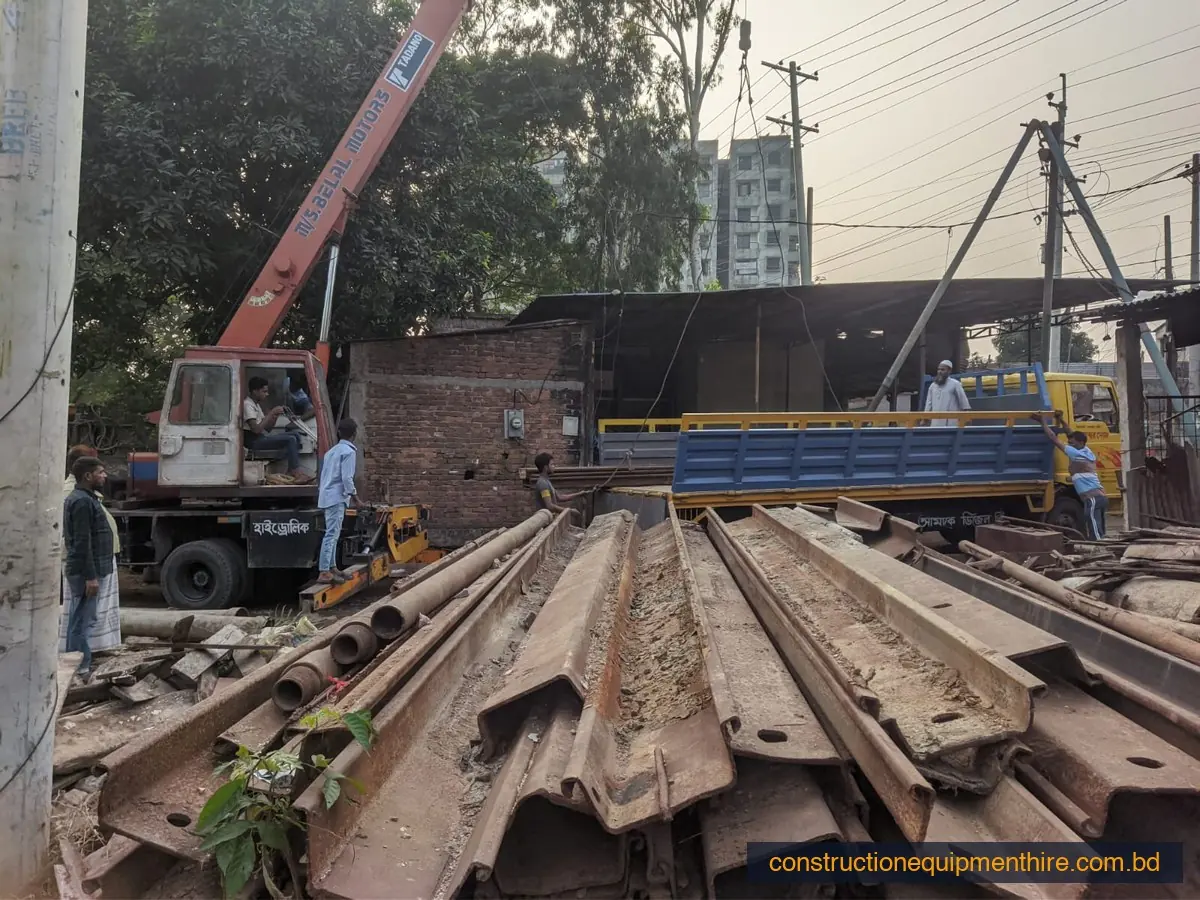 Steel sheet piles stacked beside a crane